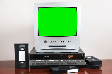 Old silver green screen TV for video and photos with built-in DVD player and a vintage video recorder from the 1980s, 1990s, 2000s next to it.