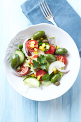 Healthy Salad with Green Olives, Baby Spinach, Cucumber, Cherry Tomatoes and Capers. Bright wooden background. Top view. Close up.