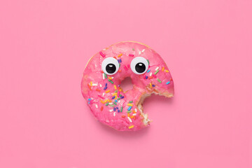 Shocked partially eaten pink donut doughnut on a matching pink background with googly eyes and copy...