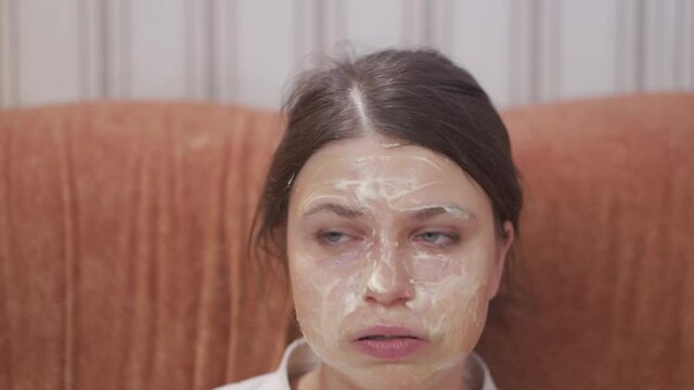 Young woman makes cosmetic mask on her face at home.