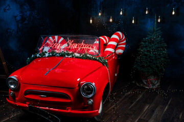 tro red car with led red inscription merry christmas on it. big christmas lollipops in the car in studio background