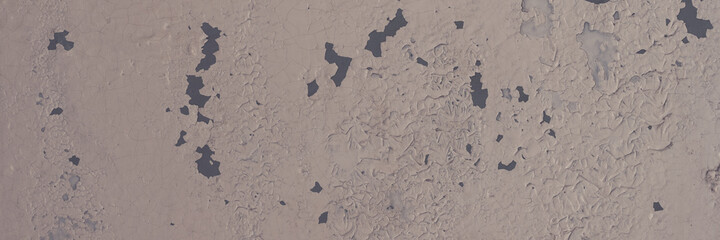 Peeling paint on the wall. Panorama of a concrete wall with old cracked flaking paint. Weathered rough painted surface with patterns of cracks and peeling. Panoramic texture for background and design.
