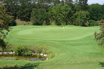 Artificial pond hazard in front of green, golf concept