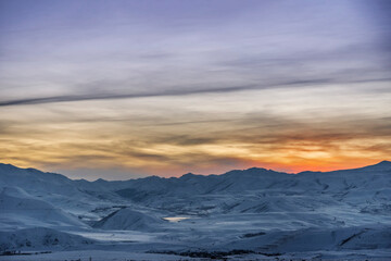 Beautiful winter landscape. The mountains peaks snow-covered on the sunset. Dramatic sky.