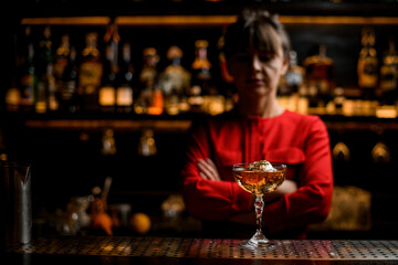 view on glass of alcoholic drink with ice cube stands on the bar counter