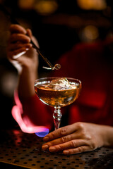 close-up view of glass with drink and ice cube that woman bartender decorates