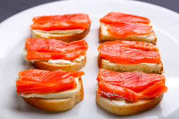 Bruschettes with butter and trout on a white plate close-up.