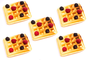 Homemade Belgian waffles with black and red raspberries on a white background