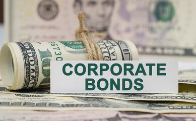On the table are bills, a bundle of dollars and a sign on which it is written - CORPORATE BONDS - obrazy, fototapety, plakaty