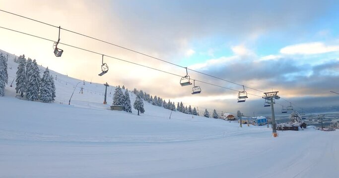 Elevated passenger ropeway for skiers. Empty chairlift on Krvavec ski resort, Slovenia. Onhill transport at ski area. Alps mountains slope under thick snow in winter season