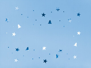 Confetti stars and trees sparkling on blue background.