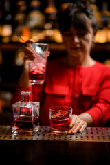glass with big piece of ice and bottle of drink stands on bar counter