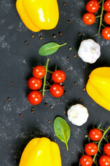 Fresh organic vegetables on black background. Flat lay. Copy space. Healthy food. Vegetarian food.Tomatoes and sweet pepper.Garlic. Vertical orientation