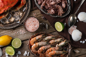 view from above of plates with assorted seafood served with spices on rustic wooden background. Cooked crab, shrimps and baby octopuses for dinner. Seafood concept. Delicious healthy meal.