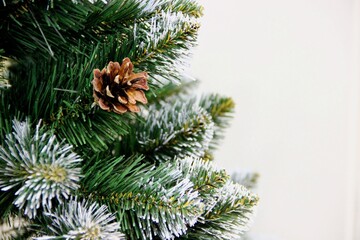 a fir cone on a green with a white touch of artificial pine branch, a place for text on the right. Festive background