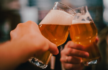 Close-up view of a two glass of beer in hand. Beer glasses clinking in bar or pub