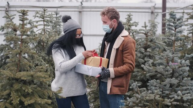 A lovely, young couple is having fun at Christmas tree market. Concept for love, New Year, Christmas and shopping for gifts