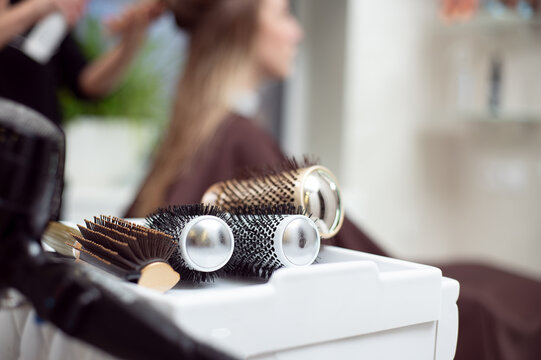 Cropped view of professional hairdresser tools . Closeup of round brushes on the background of a hairdresser while working