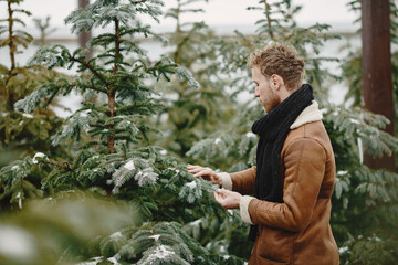 Naklejka na ściany i meble Winter concept. Guy in a brown coat. Salesman of Christmas Tree.