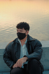 Asian man sit at riverside with black fabric face mask - 403316755