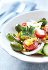 Healthy Salad with Green Olives, Baby Spinach, Cucumber, Cherry Tomatoes and Capers. Bright wooden background.