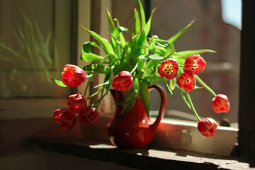 Ceramic vase with tulips standing on the a vintage window sill of Tuscan window