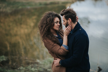 stylish hipster caucasian couple hugging at lake in autumn. man and woman in love in modern outfit