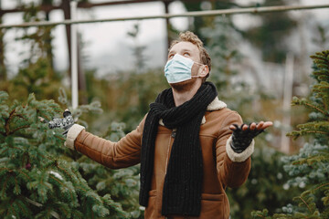 Winter concept. Guy in a brown coat. Salesman of Christmas Tree. Coronavirus theme.