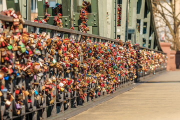 Many locks on the green bridge railing of the iron bridge in Frankfurt over the river Main. Locks of love in different colors in the sunshine