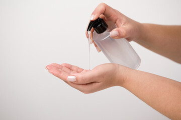 Close up of woman hand using alcohol gel for cleaning and sanitize. Gel pump dispenser on white background. Prevent the spread of germs and avoid infection from corona virus