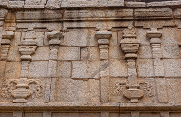 Hampi, Karnataka, India - November 4, 2013: Prasanna Virupaksha underground Shiva Temple. Brown stone wall with pillars as fresco sculptures.