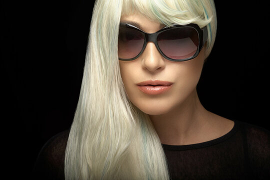Fashion portrait of an attractive blond woman in sunglasses on black background