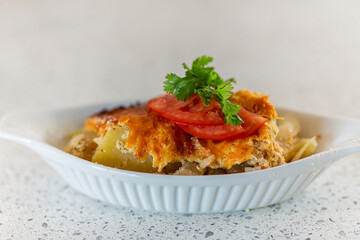 Closeup shot featuring delicately set side dish, garnished with tomatoes, and green leaves on top, with the plate set on marble shelf