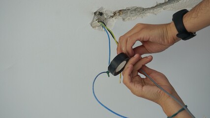 Manos de electricista manipulando cables. Instalación de red eléctrica sobre techo a través de una regata.  - obrazy, fototapety, plakaty