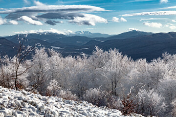 Zimowy krajobraz górski. Widok na dolinę między Rawkami a Tarnicą z ukraińskimi Karpatami na horyzoncie, Bieszczady, Polska