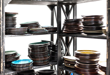 Stacks of craft ceramic or pottery plates on a shelfs on white background