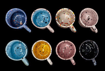 Arranged colorful craft ceramic or pottery mugs, above view, black isolated