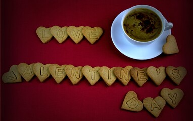love Valentine's day napis z ciasteczek przy kawie,  czerwone tło, ciastka serduszka © Anna