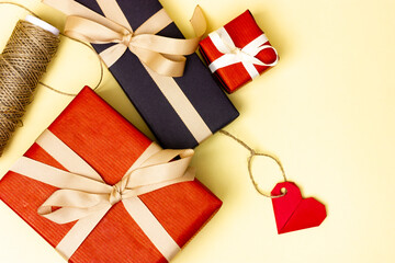 Two gifts wrapped in red and black paper with a beige ribbon on a yellow background. Gift wrapping...