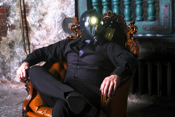 Obraz na płótnie Canvas cosplay of a guy in a gas mask sitting on a leather chair with glowing eyes