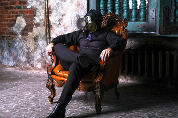 Fototapeta na wymiar cosplay of a guy in a gas mask sitting on a leather chair with glowing eyes