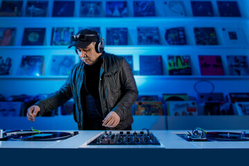 Hombre Dj mezclando música en un tornamesa con discos de vinil, y escuchando en los audífonos....