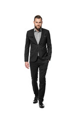 Attractive businessman in dark suit and shirt walking towards camera with an intense look. White background.