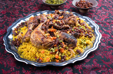 Traditional fried Arabic chicken majboos with chicken leg and jeweled rice served as close-up in a rustic oriental tray