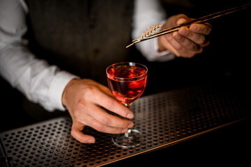 barman's hand accurate holds glass of drink and decorates it with wheat spikelet