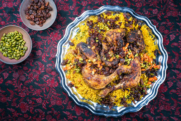 Traditional fried Arabic chicken majboos with chicken leg and jeweled rice served as top view in a rustic oriental tray