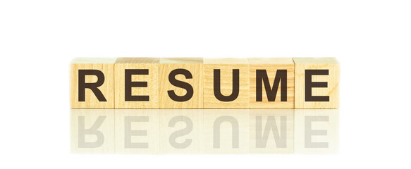 Wooden blocks with the text: resume. The text is written in black letters and is reflected in the mirror surface of the table.