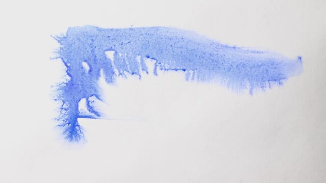 brush strokes of watercolor blue paint with stains on a sheet of white paper.