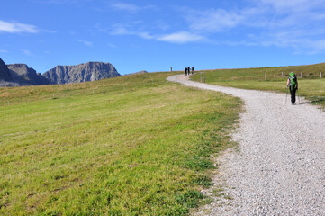 Ludzie idą szlakiem pośród zielonych pastwisk, Dolomity