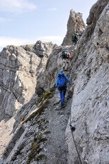 Ludzie przechodzą wąską, skalną ścieżką na via ferracie, Dolomity, Włochy - obrazy, fototapety, plakaty